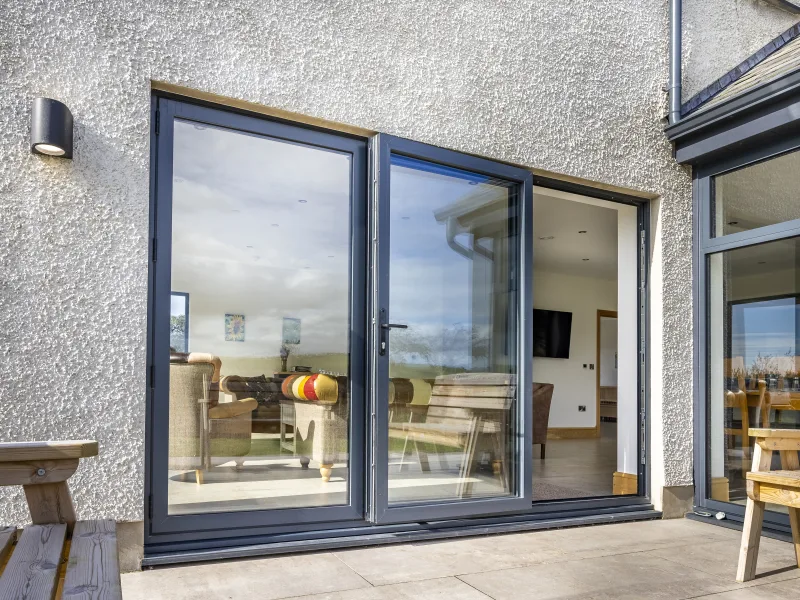 Anthracite grey aluminium bifold doors installed on a rendered property in the North West